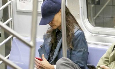 Atriz famosa Kate Holmes sentada no metrô mexendo no celular