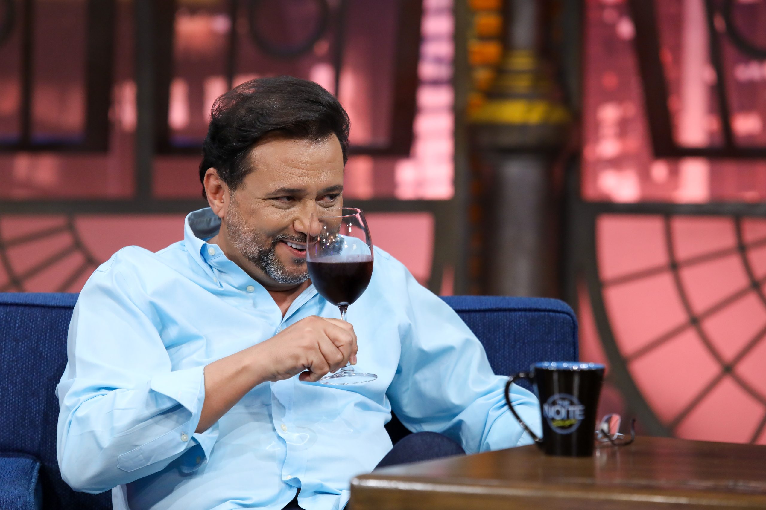 Geraldo Luis segurando uma taça de vinho no The Noite